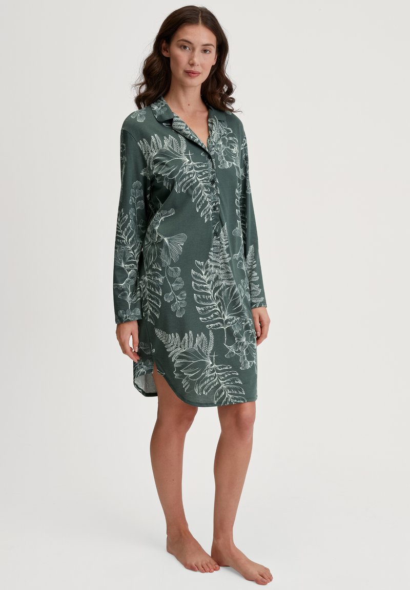Vestito da notte con maniche lunghe di colore verde scuro con motivi floreali bianchi, caratterizzato da un bottone frontale e spacco ai lati dell'orlo. Tessuto morbido.