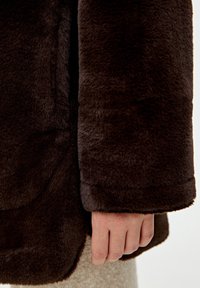 Brown faux fur coat with a soft texture, featuring a slightly oversized silhouette and a cuffed sleeve. Visible seam details.