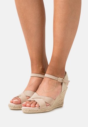 Sandalias cuña de ante beige con tiras cruzadas, hebilla en el tobillo y suela envuelta en yute, con un acabado texturizado y diseño de punta abierta.