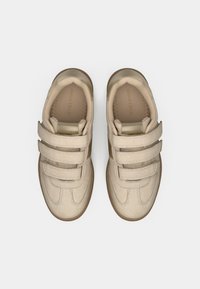 Baskets beiges avec trois bandes Velcro, en suède et cuir, à bout rond et avec une semelle en gomme texturée, mettant en avant des détails cousus.