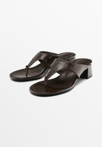 Brown leather sandals with a T-strap design, textured finish, and a low block heel, featuring a circular accent at the center.