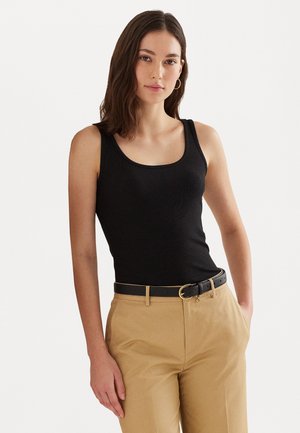 Svart ribbad linne med rundad halsringning, kombinerad med beige högmidjade byxor och ett svart bälte med en guldfärgad spänne.