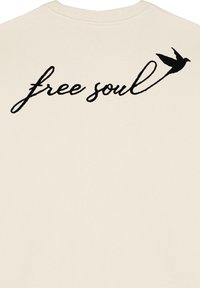 Felpa beige con il testo scritto a mano "free soul" in nero, insieme a un grafico di un uccello contornato. Tessuto morbido e textured.
