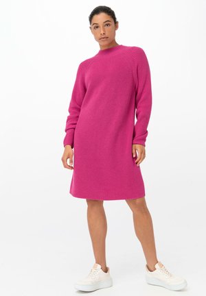 Gehaakte jurk in felroze met een hoge halslijn en lange mouwen, met een comfortabele pasvorm en textuurstof. Gecombineerd met witte sneakers.