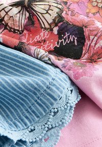 Multikleurige stof met vlinders en bloempatronen in roze en blauw. Gestructureerd blauwe katoen met witte strepen en ingewikkelde kantdetails.
