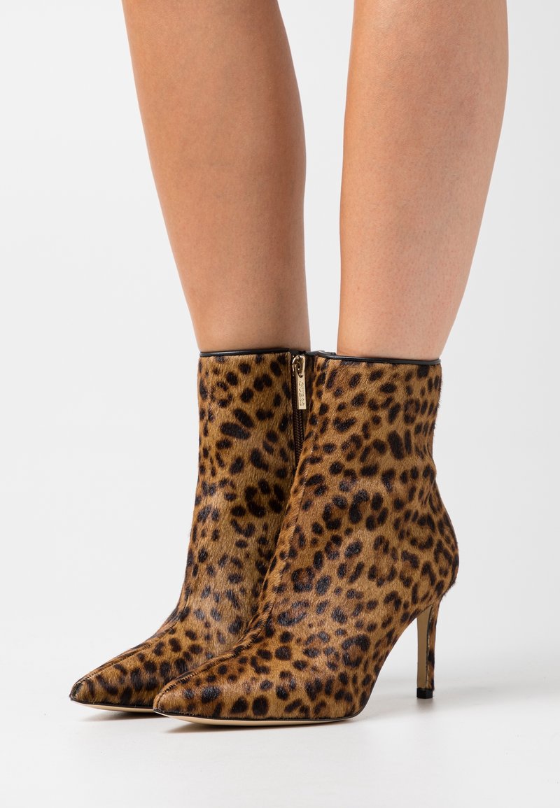 Botines de piel con estampado de leopardo hechos de material texturizado con punta puntiaguda y tacón delgado. Presentan una cremallera dorada en el lateral.