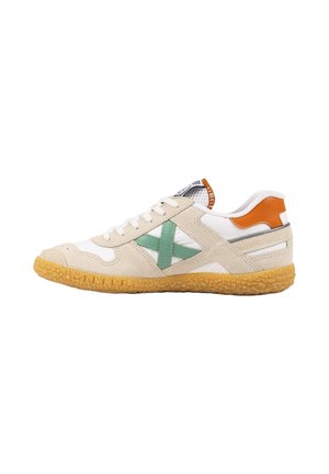 Zapatilla de perfil bajo en beige y blanco con una X verde lateral, parche naranja en el talón, cordones blancos y suela de goma texturizada.