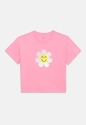 T-shirt rose à manches courtes avec une marguerite souriante à pétales blancs et visage jaune au centre sur le devant.