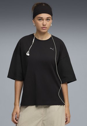 Sort oversized T-shirt lavet af en blød bomuldsblanding med korte ærmer, rund halsudskæring og et lille gråt logo på brystet.