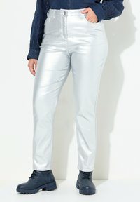 Pantalones metálicos plateados con una cintura alta, diseño de pierna recta y corte ajustado. Combinados con botas azul marino con cordones para un contraste.