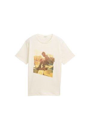 T-shirt bianco in cotone con una grande stampa grafica di uno skateboarder in azione, con una palette di colori sbiaditi in giallo e marrone.