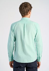 Vaalean mintunvihreä pitkähihainen paita, joka on valmistettu teksturoidusta kankaasta. Siinä on tavallinen kaulus ja nappilisät hihansuissa, sekä takana olkapäiden yksityiskohta.