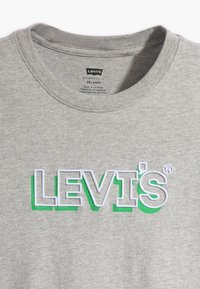 Camiseta de algodón gris con cuello redondo relajado, con el logotipo elevado "LEVI'S" en bordado blanco y verde en la parte delantera.