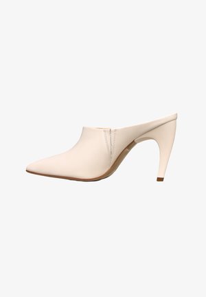 Mule beige con punta appuntita, tacco curvo di media altezza e dettaglio di cucitura minimale vicino all'apertura su sfondo bianco.