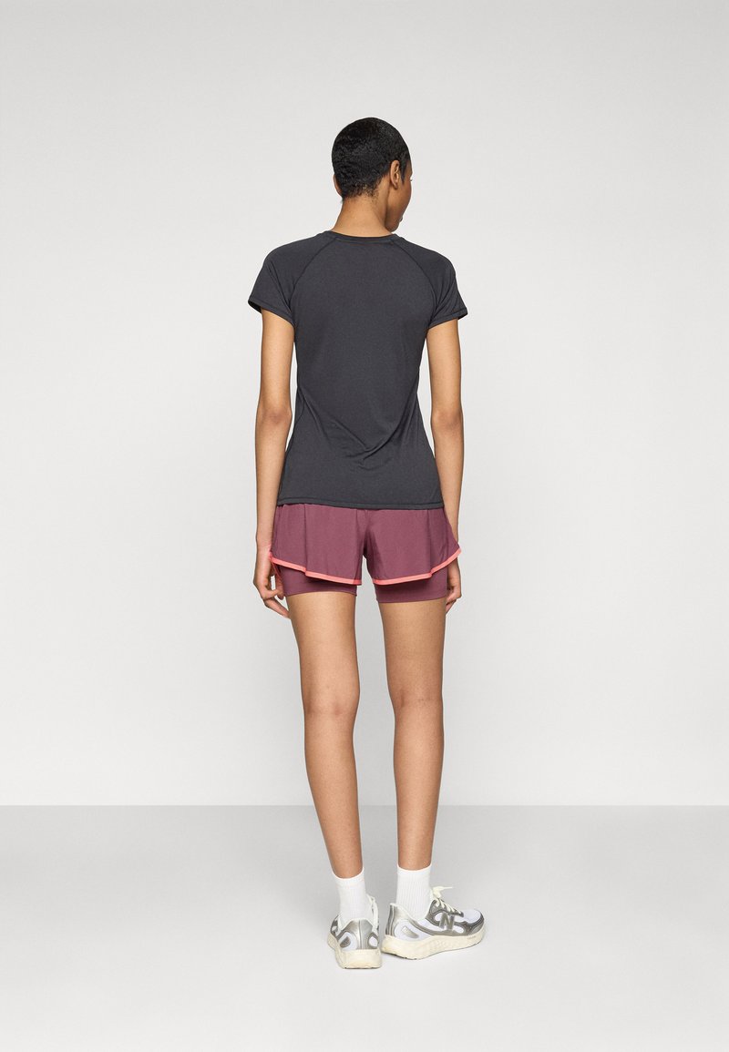 Top corto de color gris oscuro con mangas cortas, combinado con pantalones cortos burdeos en capas con un ribete rosa, usados con calcetines blancos y zapatillas plateadas.
