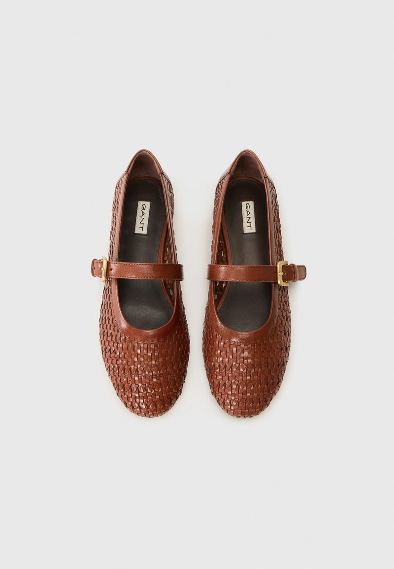Chaussures en cuir tressé marron avec un bout arrondi, une bride de cheville et une boucle dorée. Intérieur lisse, semelle plate, design minimaliste.