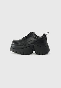 Sorte platform sneakers lavet af glat læder, med en tyk, rillede sål, rund tå, snørebåndsdesign og en bagpåtrækning.
