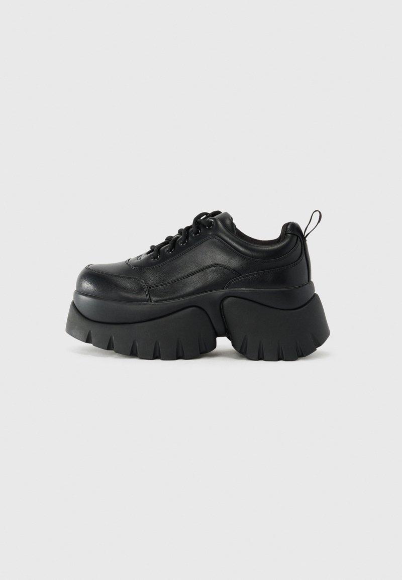 Sorte platform sneakers lavet af glat læder, med en tyk, rillede sål, rund tå, snørebåndsdesign og en bagpåtrækning.