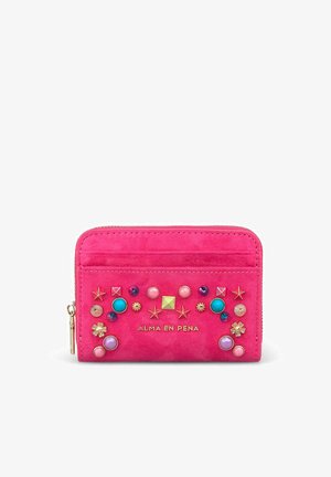 Cartera de ante rosa brillante decorada con tachuelas y cuentas multicolores y el logo "Alma en Pena" en tono dorado en la parte frontal.