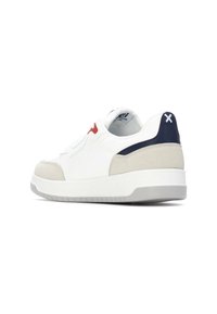 Zapatilla blanca con parte superior de cuero liso y acentos de gamuza color beige. Presenta detalles en rojo y azul marino, un cuello acolchado y suela de goma.