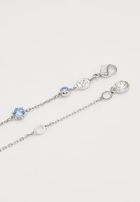 Silberne Kettenarmband mit blauen und klaren Edelsteinen, sechseckigen und runden Charms sowie einem Karabinerverschluss für sicheren Halt.
