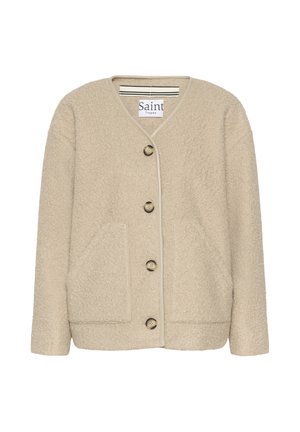 Bēšs teksturēts žakete ar V-veida izgriezumu, priekšējām kabatām un pieciem pogām. Akcentēta ar gaiša toņa apmalēm.