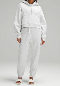 Sweat à capuche gris court avec une fermeture éclair à l'avant et une poche kangourou, assorti à un pantalon de survêtement avec une taille à cordon et des chevilles resserrées.