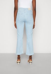 Vaaleansiniset, korkeavyötäröiset farkut levenevällä lahkeella ja viimeistelemätön helma. Mukana kaksi takataskua ja vanhanvalkoinen etiketti vyötäröllä.