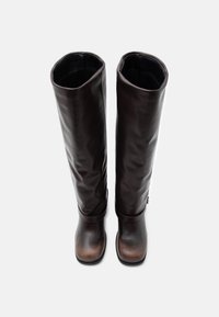 Ζεύγος ψηλών, σκούρων καφέ δερμάτινων μποτών με στρογγυλεμένες μύτες και ελαφριές ρυτιδώσεις, σε θέαση από πάνω πάνω σε απλό λευκό φόντο.