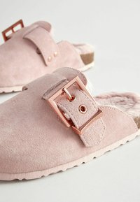 Rosa mockaskor i slip-on design har en texturerad yta, ett mjukt och fluffigt inre samt en rektangulär spänne i roséguld med nitar.