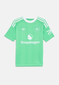Zelena nogometna majica s bijelim naglascima, kratkim rukavima i dizajnom s tri pruge. Uključuje grb Manchester Uniteda i logo "Snapdragon".