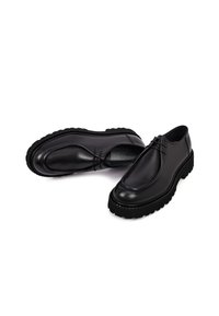 Zapatos de cuero negros con punta redondeada, suela texturizada y costuras decorativas. Presentan una plataforma gruesa con un acabado suave.