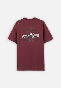 T-shirt bordeaux avec un graphique d'une moto et d'une planche de surf, le texte "OXBOW" au-dessus, et une petite patch "OXBOW" près du col à l'arrière.