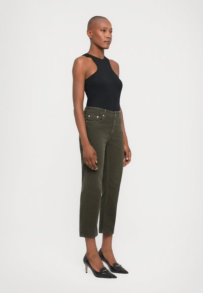Black sleeveless bodysuit, olive green corduroy pants with five pockets, slim fit, ankle-length, black pointy-toed heels with gold accent.