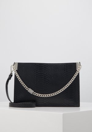 Sort rektangulær clutch med tekstureret mønster og aftagelig sølvkæde rem, der hviler på en hvid overflade.