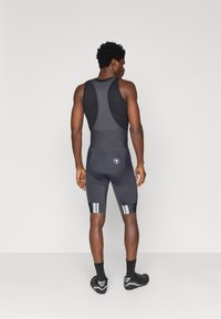 Mustad jalgrattasadula lühikesed püksid, millel on võrkmaterjalist ülemine osa, hallid triibud jalgadel ja polsterdatud istmeosa mugavuse tagamiseks.