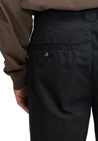 Tmavomodré nohavice vyrobené z bavlneného zmesi, s zadným vreckom so zaobleným gombíkovým uzáverom a jemnou textúrou.