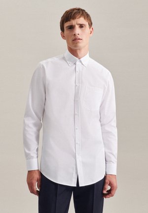 Witte langwerpige knopshirt gemaakt van geweven stof, met een klassieke kraag, een borstzak en een afgeronde zoom.