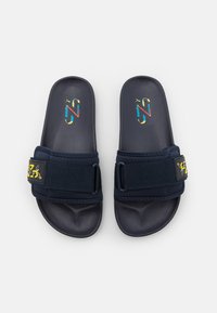 Chanclas de color navy con suela de plástico suave, correa de tela y detalle de logo colorido. Correa ajustable para un mejor ajuste y comodidad. Diseño plano.