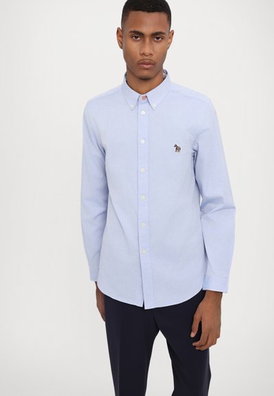 Chemise boutonnée à manches longues bleu clair en coton, avec un col, des boutons à l'avant et un petit logo de cheval multicolore brodé sur la poitrine.