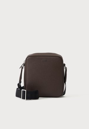 Petit sac bandoulière en cuir marron avec une bandoulière noire réglable et des boucles argentées, embossé avec le logo BOSS au centre devant.