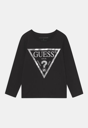 Czarna koszula z długim rękawem z dużym srebrnym trójkątnym logo z przodu z napisem „GUESS U.S.A. Washed Jeans” i znakiem zapytania w środku.
