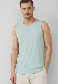 Hellblaues, ärmelloses Tanktop mit einem runden Halsauschnitt und einem weichen, strukturierten Stoff. Ein kleines Logo ist auf dem Brustbereich sichtbar.