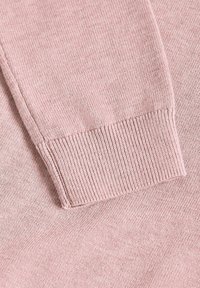 Gros plan d'une manche de pull tricotée rose douce avec un bord-côte et une texture fine.