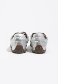 Srebrne, metaliczne sneakersy o zaokrąglonym kształcie, z teksturowaną, brązową gumową podeszwą i oznaczeniem na pięcie. Prosty design z akcentami.