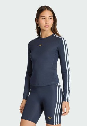 Marineblåt atletisk langærmet top og matchende shorts med hvide striber og gyldne logo-accenter. Glat, elastisk stof, tætsiddende design.
