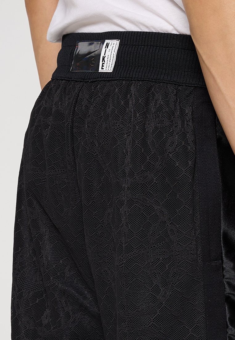 Shorts Nike noirs en tissu maillé texturé. Comprend une taille élastique noire et une étiquette de logo à l'arrière de la taille.