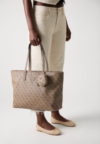 Brown logo-printed tote bag with two handles and a detachable round pouch. Smooth texture, rectangular shape, and subtle gold hardware.