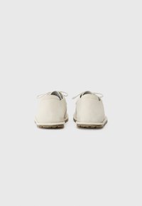 Pantofi din suede bej cu spate rotunjit, două gauri pentru sireturi și tălpi din cauciuc texturat. Design minimalist, fără logo-uri sau accente vizibile.