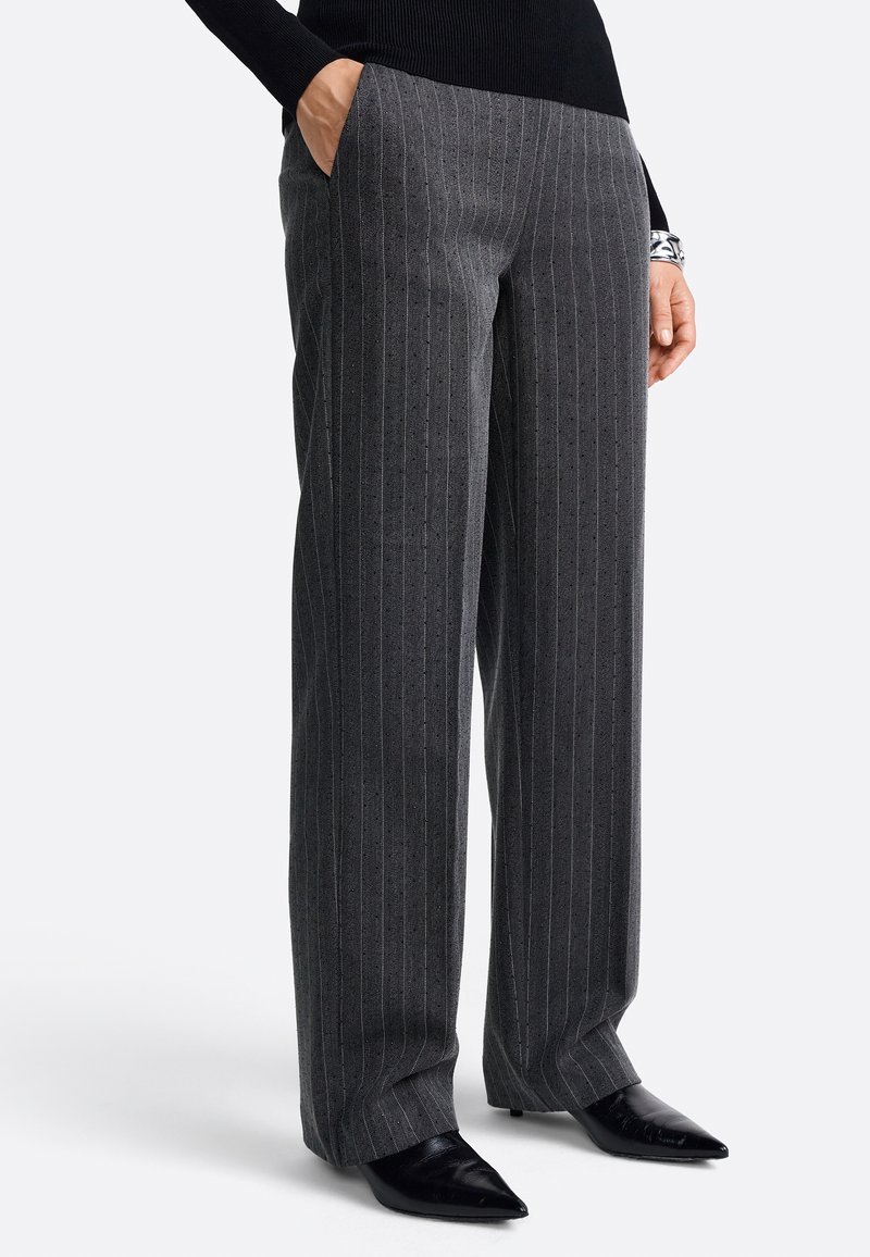 Grijze gestreepte broek met een losse pasvorm en zakken, gemaakt van textuurstof. Gecombineerd met puntige zwarte schoenen.